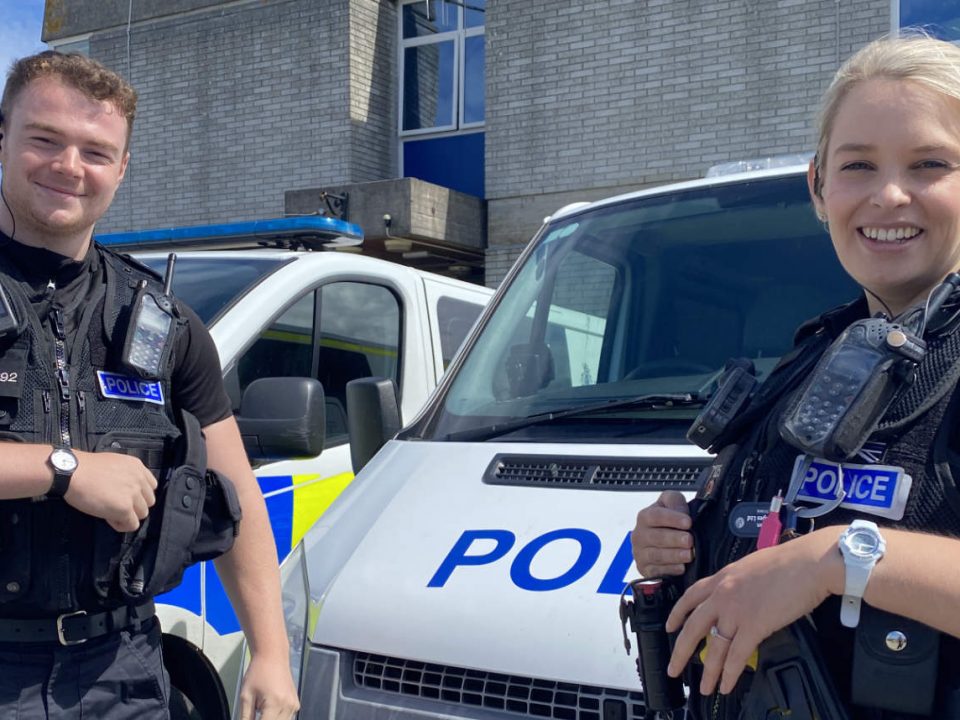 Two officers stood infront of a stationary Police van